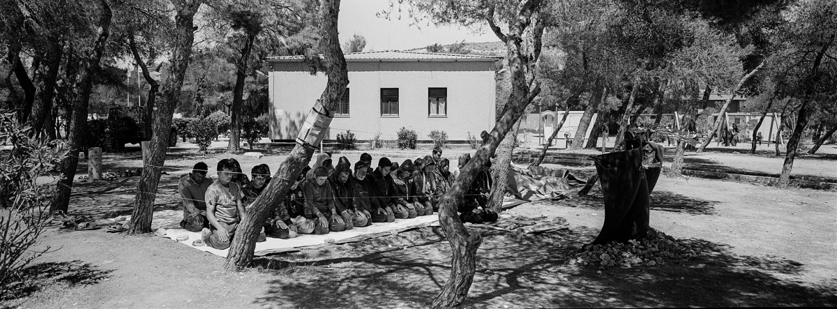 A group of men pray at the Schisto camp for refugees and migrants, near Athens.