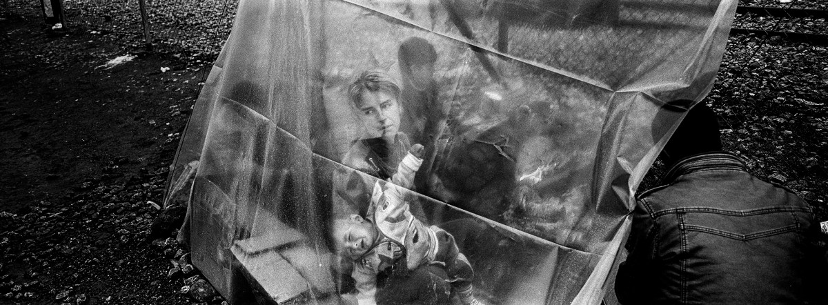 A migrant woman holds a child inside a tent while it rains at a makeshift camp at the Greek-Macedonian border, near the village of Idomeni.