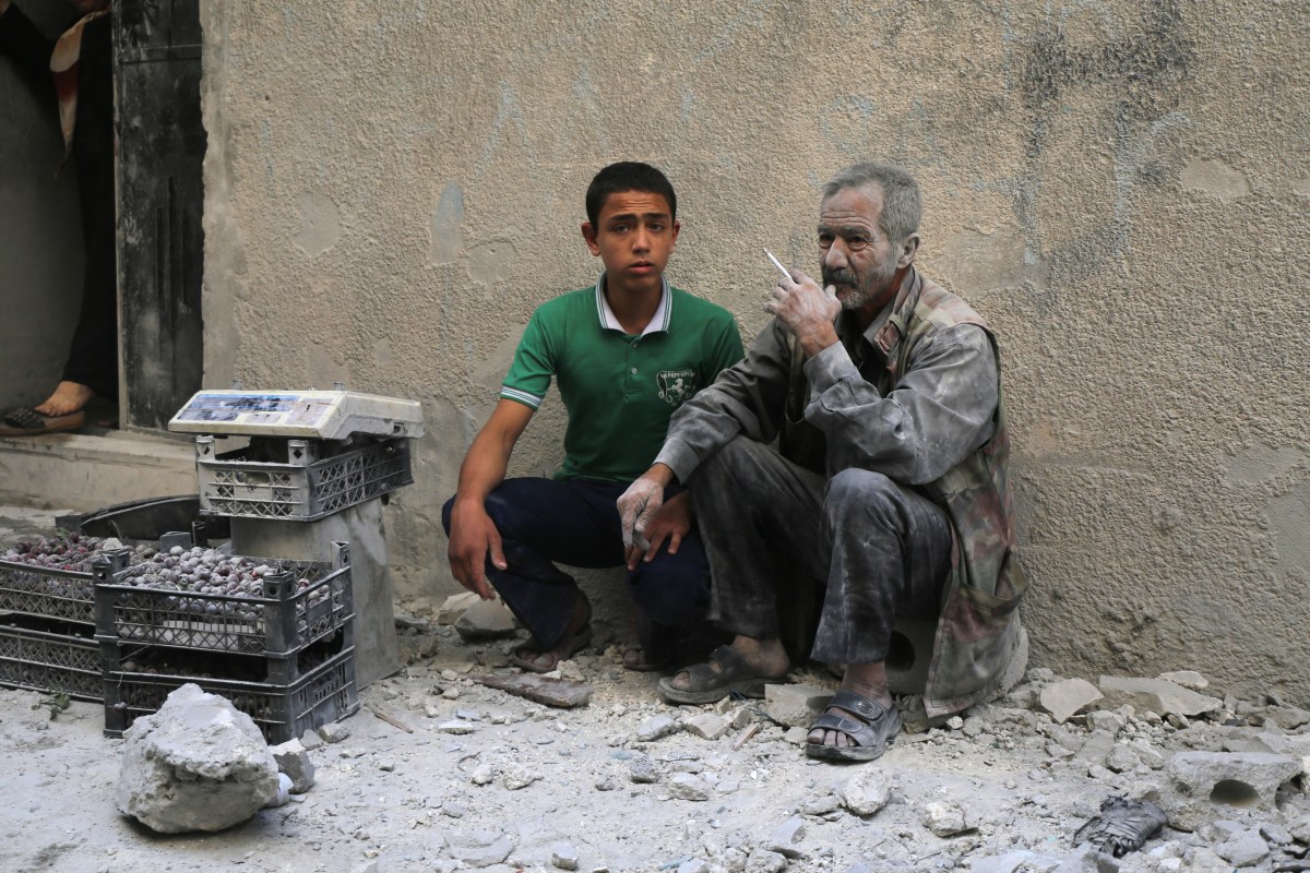 A man covered with dust sits on a street following a reported airstrike by Syrian government forces in the rebel-held neighborhood of Sukkari in Aleppo on May 30, 2016.