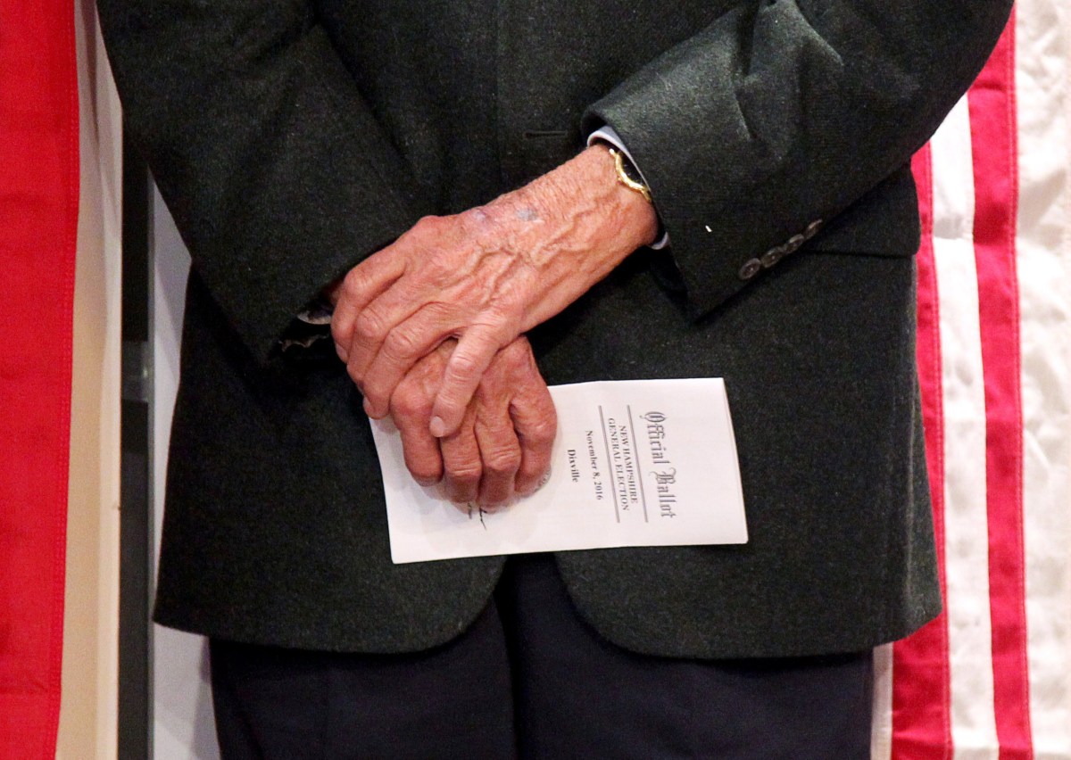 A voter holds onto his ballot as he waits to cast it in the U.S. presidential election at midnight in tiny Dixville Notch