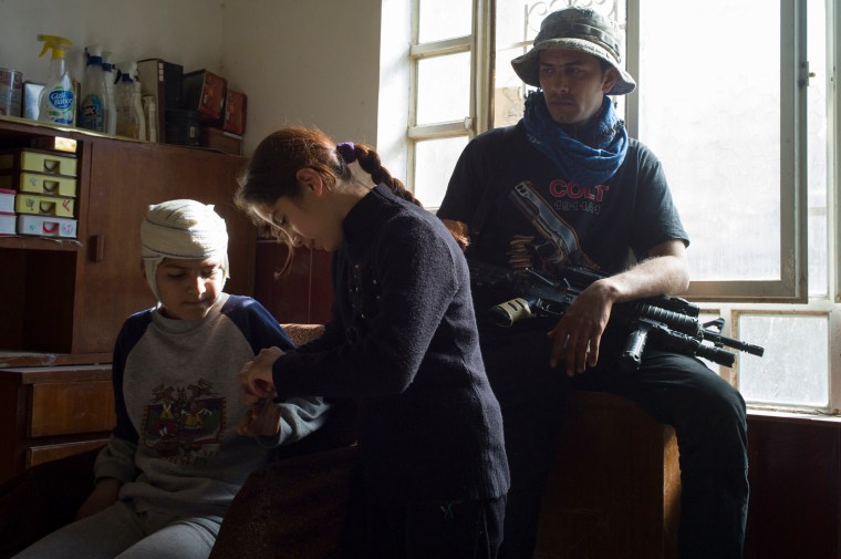 Zainab (age, 10) checks the scratches at the hands of her cousin Murtadha (age, 12), who was injured when a mortar fall at their house in Mosul, while a soldier of ISOF sits in the house where they stay next to the frontline.With their families they moved to another house in a different area of the city, which nowadays became a battlefield as the Iraqi military forces progress in offensive against IS Mosul, Iraq.