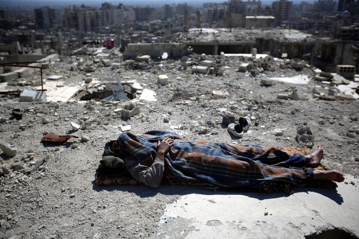 A man sleeps on the roof of a damaged building in the Barzeh neighborhood of Damascus on Feb. 17. Mohammed BadraÃ¢ÂÂEPA