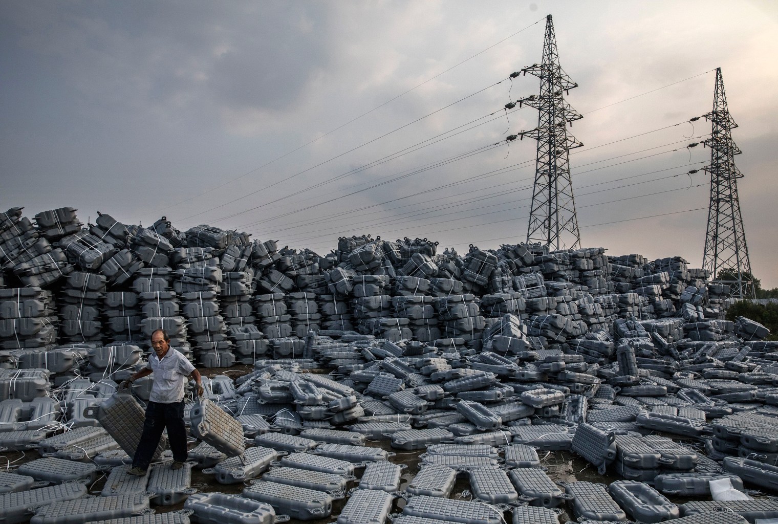 A Chinese worker carries flotation devices used to support panels.