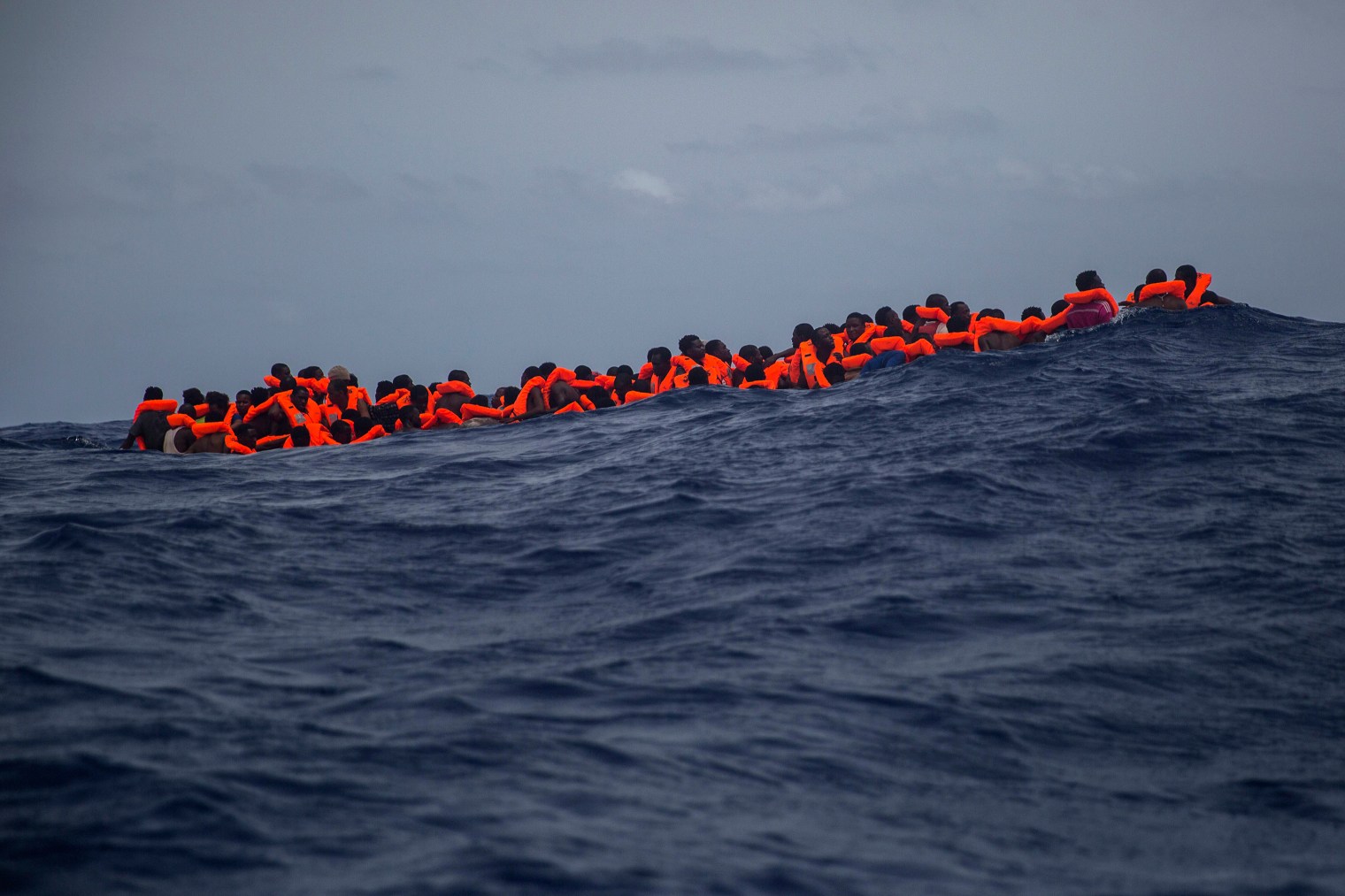 Sub-Saharan migrants who received life jackets wait to be transferred from the rubber boat to the Open Arms vessel of the Spanish NGO.