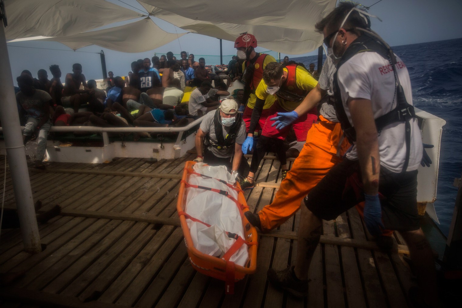 Aid workers recover dead bodies of migrants from inside het rubber boat.