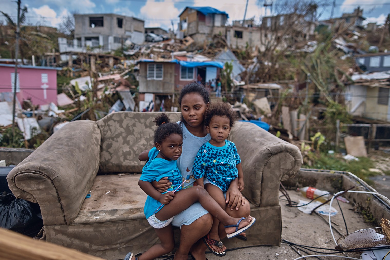 Darieliz Michelle Lopez, her 20-month-old son and three-year-old daughter sit for a portrait on the sofa where her apartment no longer stands in San Isidro, Puerto Rico, on Sept. 28, 2017.