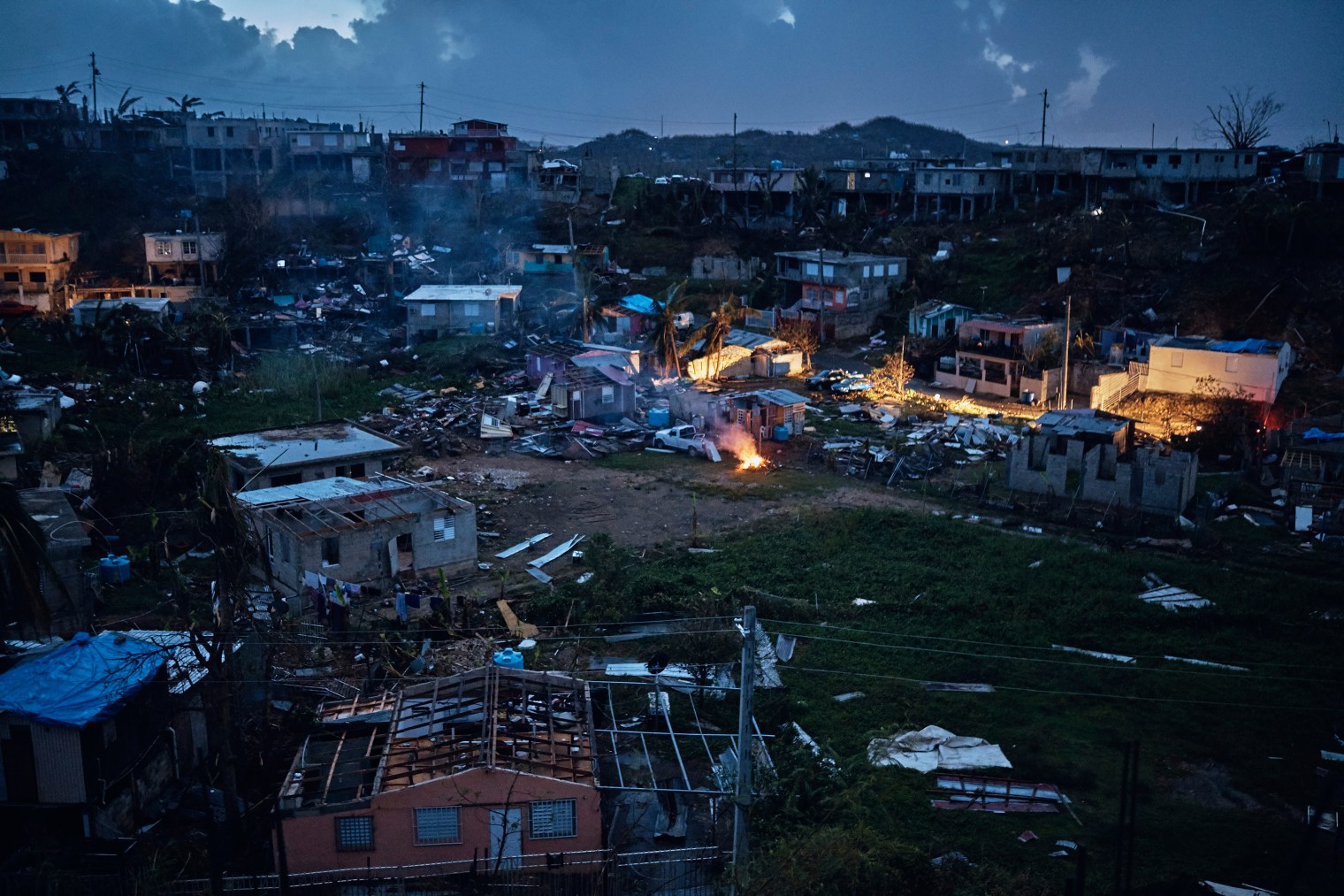 A man makes a fire in between damaged houses after sunset in San Isidro, Puerto Rico, on Sept. 28, 2017.